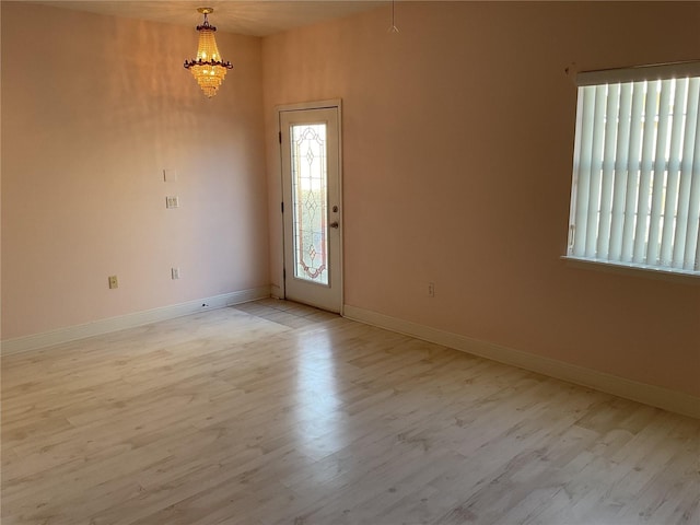 empty room with a chandelier and light hardwood / wood-style flooring