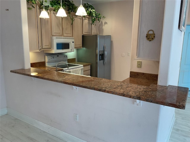 kitchen with pendant lighting, white appliances, and kitchen peninsula