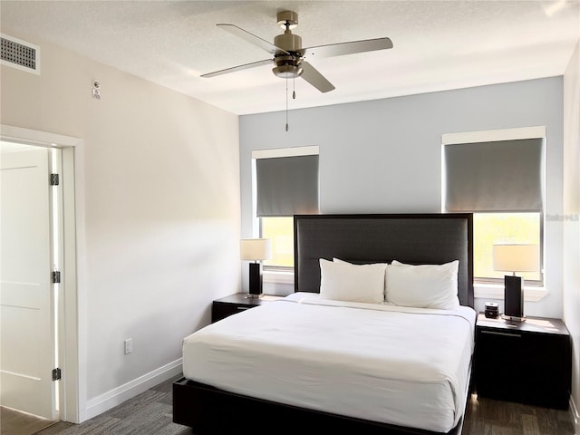 bedroom featuring multiple windows, ceiling fan, wood-type flooring, and a textured ceiling