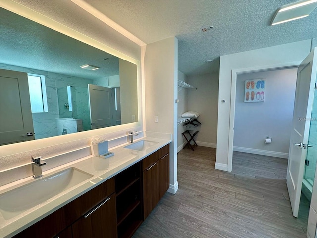 bathroom with hardwood / wood-style floors, vanity, walk in shower, and a textured ceiling