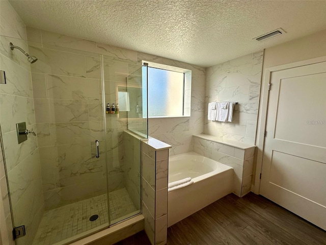 bathroom featuring separate shower and tub, hardwood / wood-style floors, and a textured ceiling