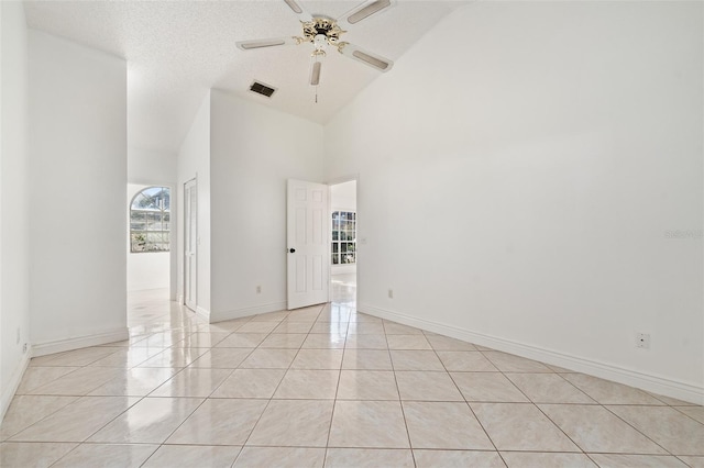 tiled empty room with a textured ceiling, high vaulted ceiling, and ceiling fan