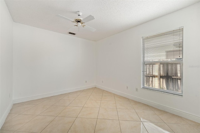 spare room with ceiling fan, light tile patterned flooring, and a textured ceiling