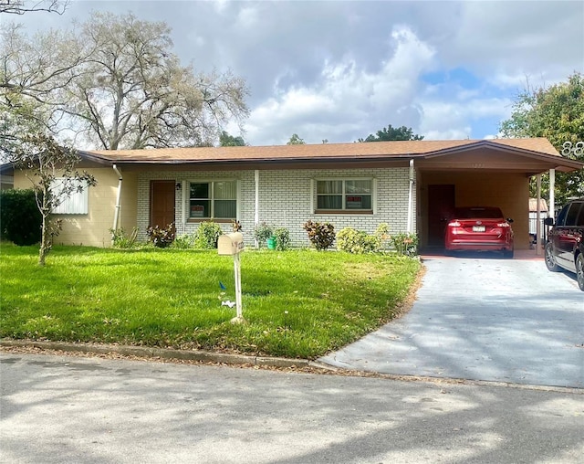 single story home featuring a carport, concrete driveway, a front lawn, and brick siding