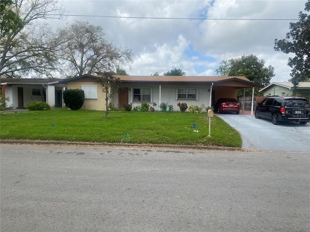 ranch-style home with an attached carport, brick siding, driveway, and a front lawn