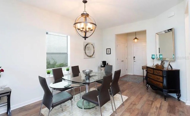 dining space featuring wood-type flooring and a notable chandelier