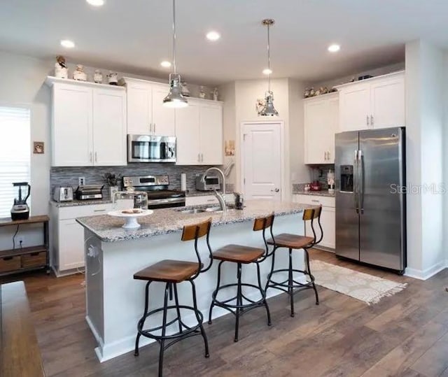 kitchen with white cabinets, appliances with stainless steel finishes, and a center island with sink