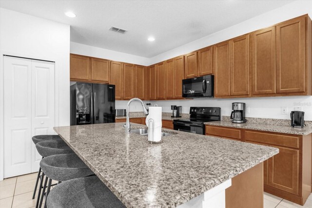 kitchen featuring black appliances, sink, and a kitchen island with sink