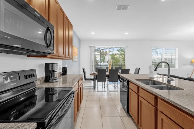 kitchen featuring light tile patterned floors, sink, light stone counters, and black appliances