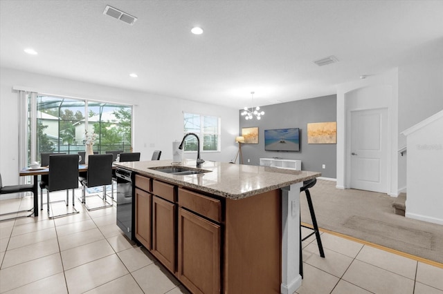 kitchen featuring light stone counters, a kitchen island with sink, sink, dishwasher, and light tile patterned flooring