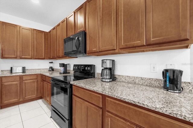 kitchen with black appliances, light stone countertops, and light tile patterned floors