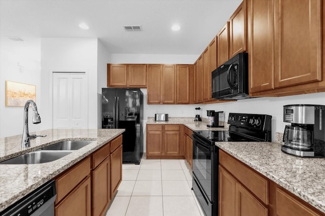 kitchen featuring light stone counters, sink, light tile patterned floors, and black appliances