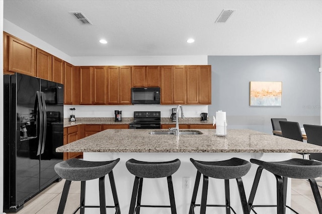 kitchen featuring a kitchen breakfast bar, sink, an island with sink, and black appliances