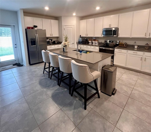 kitchen with appliances with stainless steel finishes, a kitchen island with sink, a kitchen breakfast bar, and sink