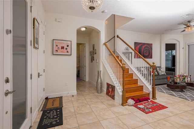 tiled foyer entrance with ceiling fan with notable chandelier