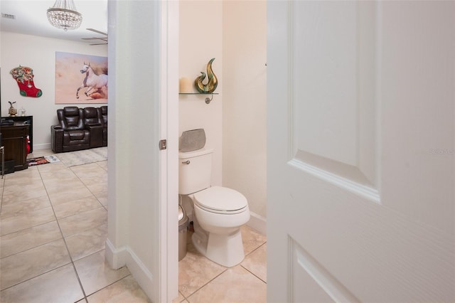 bathroom featuring tile patterned flooring, toilet, and an inviting chandelier