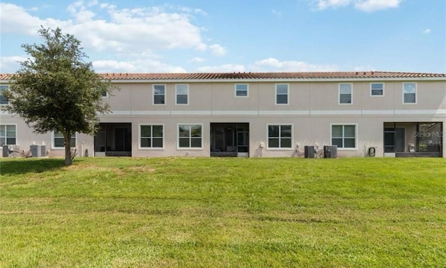 rear view of property featuring a lawn and cooling unit