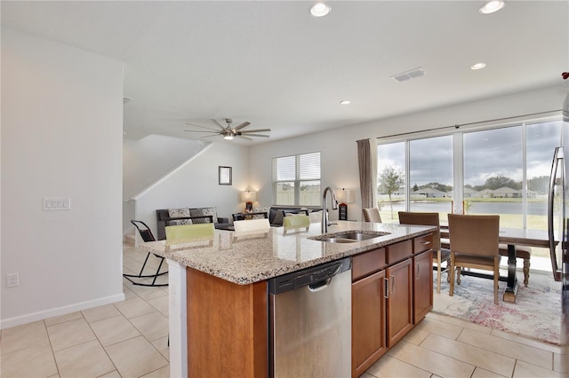 kitchen with dishwasher, a center island with sink, sink, ceiling fan, and light stone counters