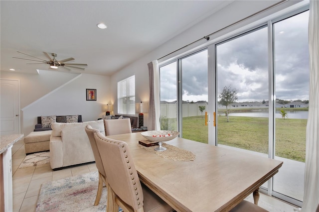 dining space with ceiling fan, a water view, and light tile patterned floors