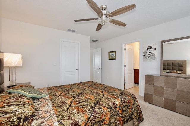 bedroom featuring ceiling fan, ensuite bathroom, and light carpet