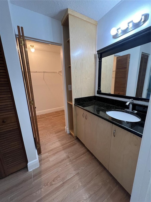 bathroom featuring wood-type flooring, vanity, and a textured ceiling