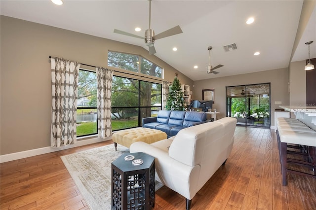 living room with ceiling fan, light hardwood / wood-style flooring, and vaulted ceiling