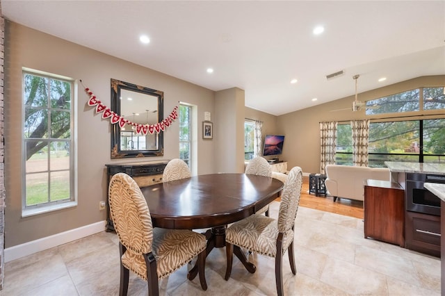 dining room with a healthy amount of sunlight, lofted ceiling, and light tile patterned floors