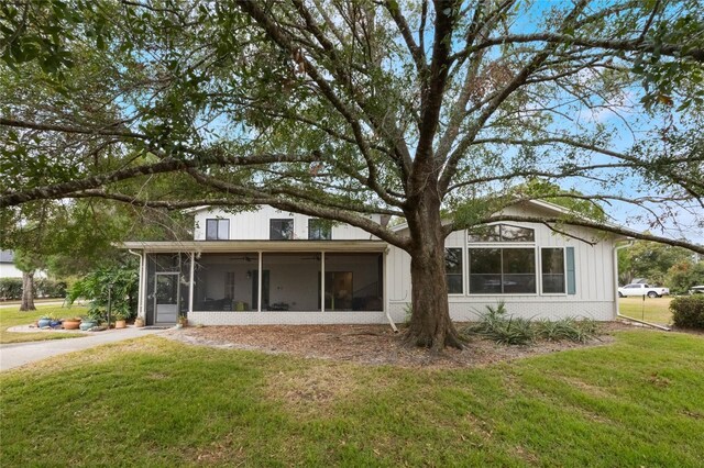 rear view of property featuring a sunroom and a yard