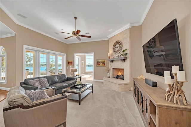 living room featuring ceiling fan, ornamental molding, a fireplace, and light carpet