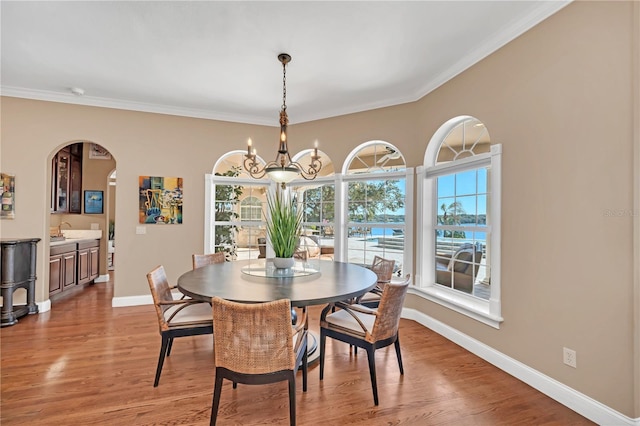 dining area featuring ornamental molding, sink, a chandelier, and hardwood / wood-style floors