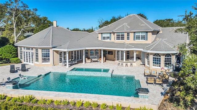 back of property featuring a pool with hot tub, a patio, and french doors