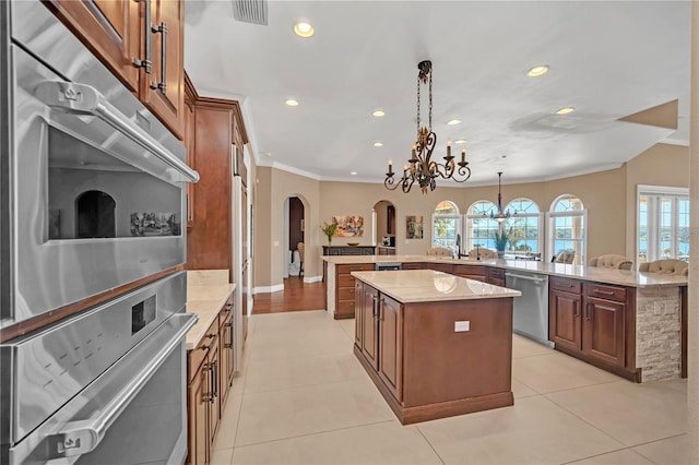 kitchen featuring a kitchen island, pendant lighting, stainless steel dishwasher, light stone counters, and kitchen peninsula