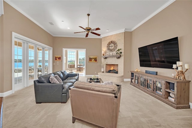 living room featuring ceiling fan, a water view, a fireplace, ornamental molding, and light carpet