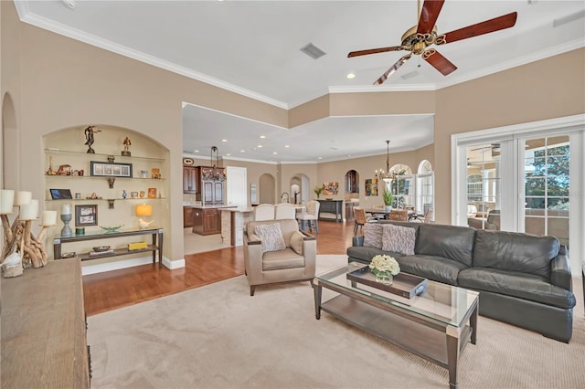 living room featuring crown molding, ceiling fan with notable chandelier, and light hardwood / wood-style flooring