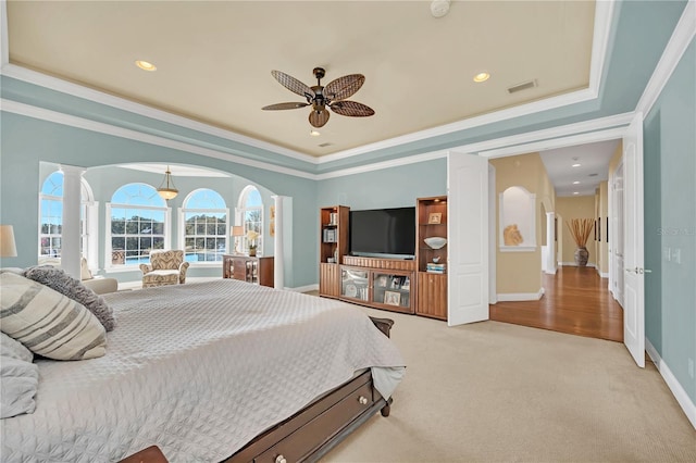 carpeted bedroom with crown molding, decorative columns, a raised ceiling, and ceiling fan