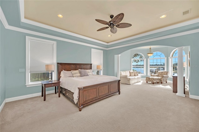 bedroom featuring a raised ceiling, ornamental molding, light colored carpet, and ornate columns