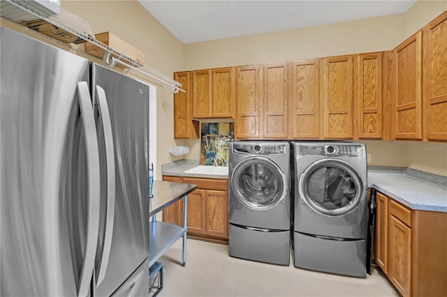 washroom featuring sink, light tile patterned floors, cabinets, and independent washer and dryer