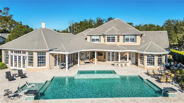 back of property with a pool with hot tub, a patio area, and french doors