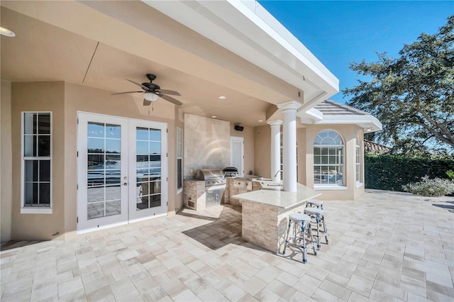 view of patio / terrace featuring an outdoor bar, ceiling fan, grilling area, french doors, and an outdoor kitchen