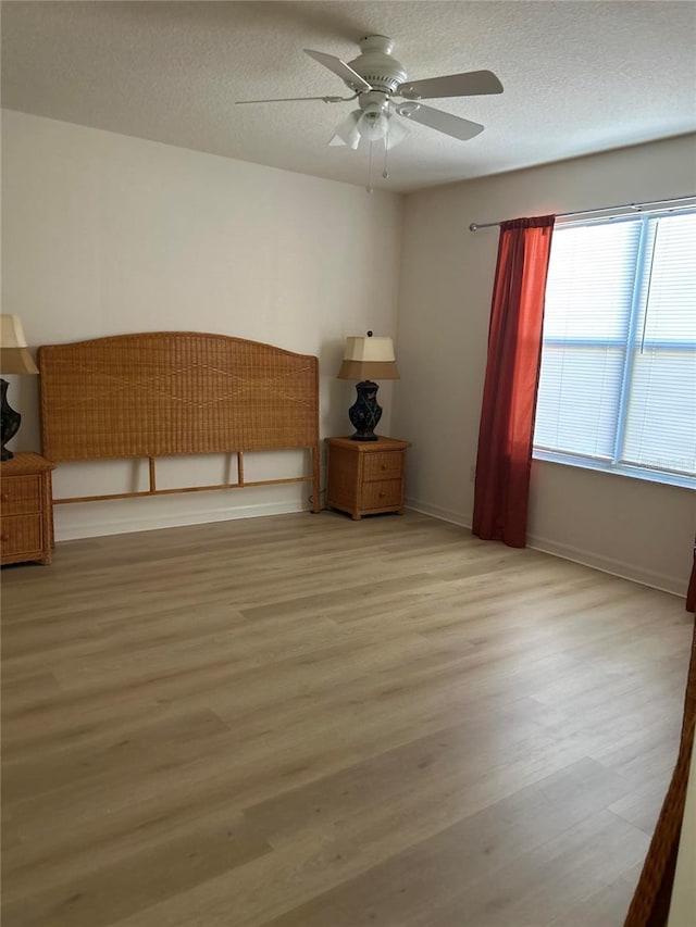 empty room featuring ceiling fan, a textured ceiling, and light hardwood / wood-style flooring