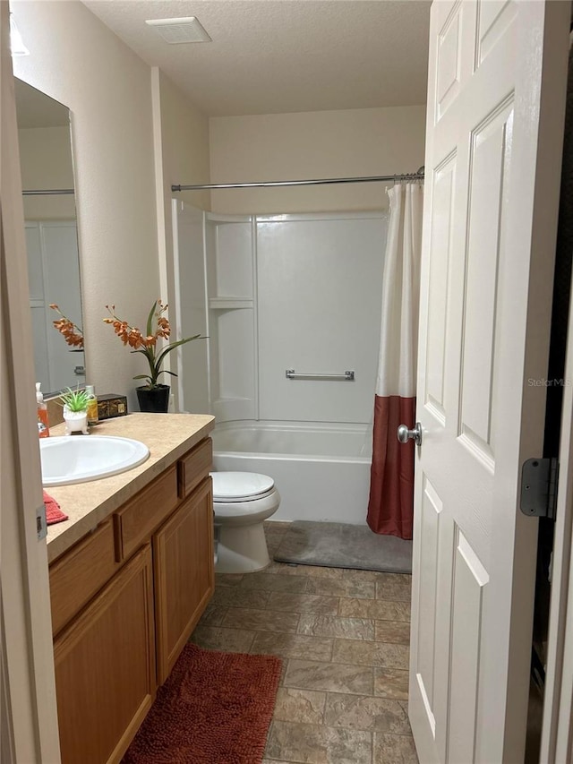 full bathroom with vanity, shower / tub combo with curtain, a textured ceiling, and toilet