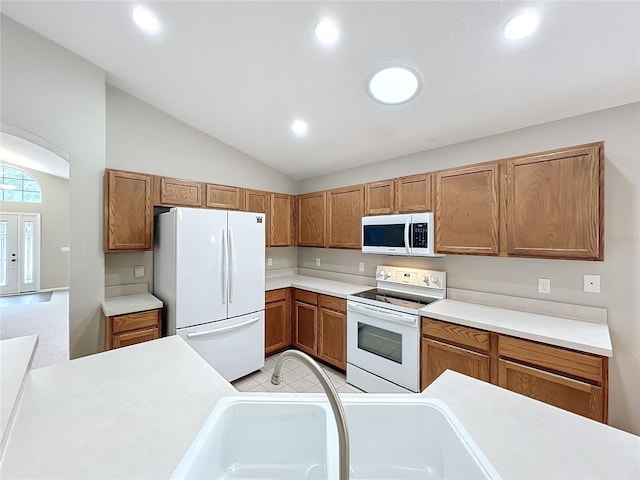 kitchen with vaulted ceiling, sink, and white appliances