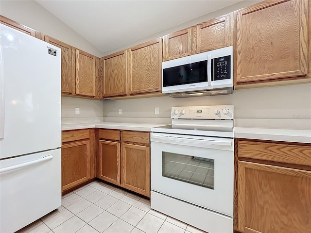 kitchen featuring vaulted ceiling, light tile patterned floors, and white appliances