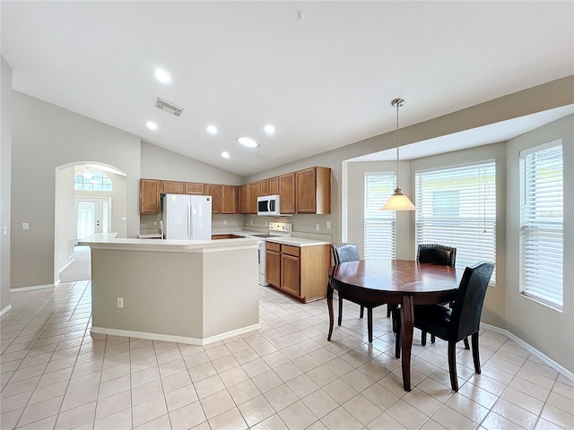 kitchen featuring decorative light fixtures, white appliances, light tile patterned floors, and lofted ceiling