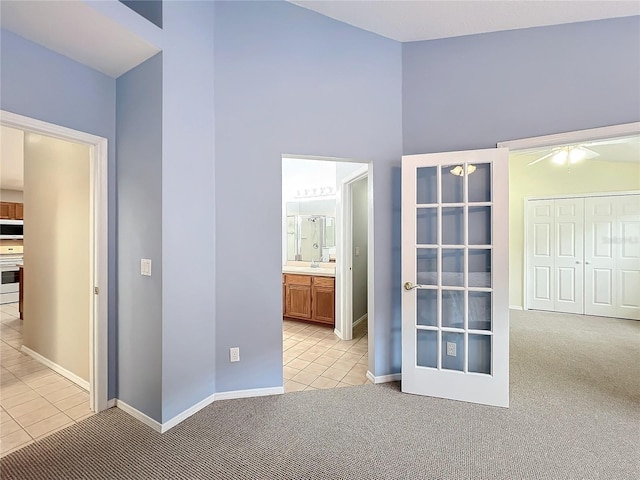 unfurnished bedroom featuring ensuite bathroom, a closet, and light colored carpet