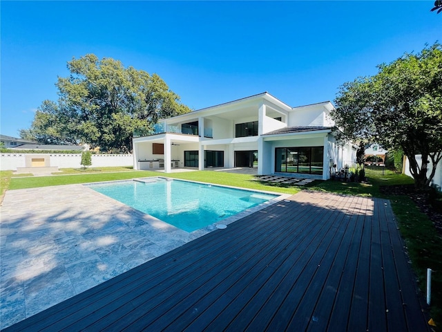 view of swimming pool with a wooden deck, a yard, and a patio