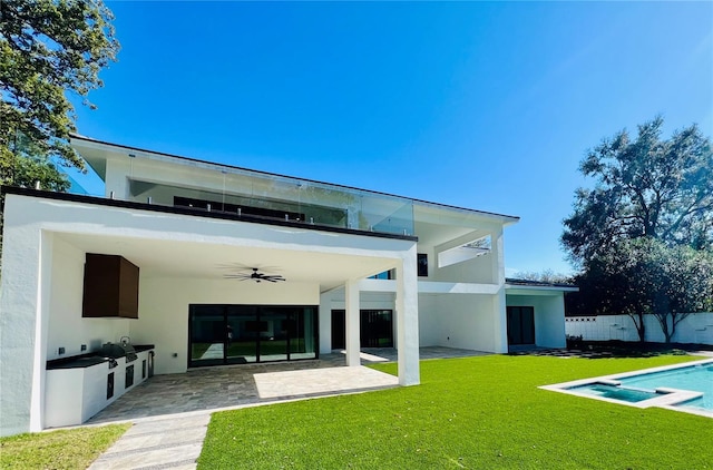 rear view of property with an outdoor kitchen, ceiling fan, a balcony, a yard, and a patio area