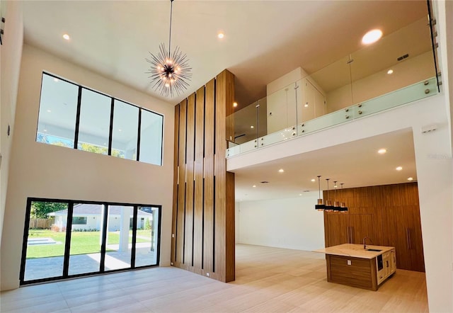 interior space with a chandelier, a towering ceiling, wooden walls, and sink