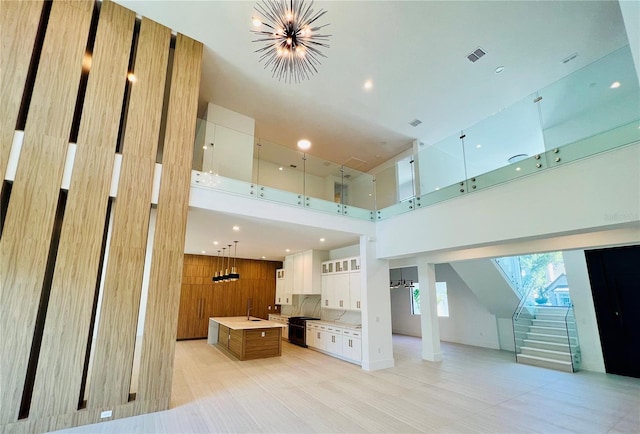 living room with a high ceiling, wooden walls, and a notable chandelier