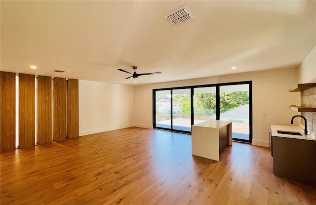 unfurnished living room with light hardwood / wood-style floors, ceiling fan, and sink